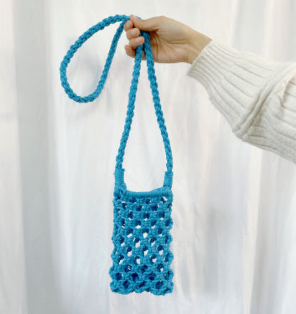 Blue crochet bag held by a hand against a white background