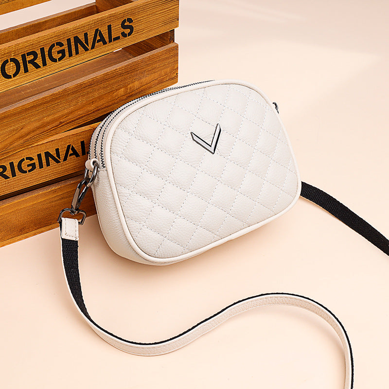 White quilted crossbody bag with a brand logo on a beige background