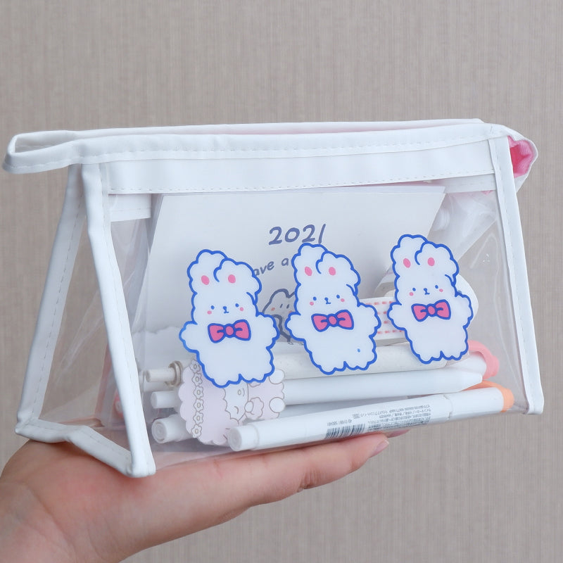 Clear pouch with cartoon bunny designs and pens held by a hand against a neutral background