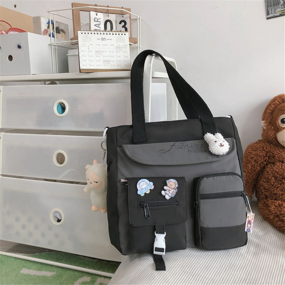 Black and gray diaper bag with plush toys on a bed next to a dresser.