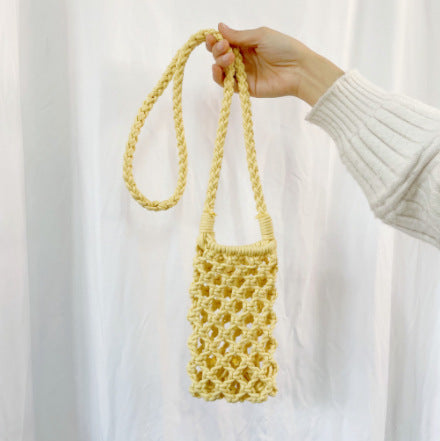 Hand holding a yellow crochet bag against a white background