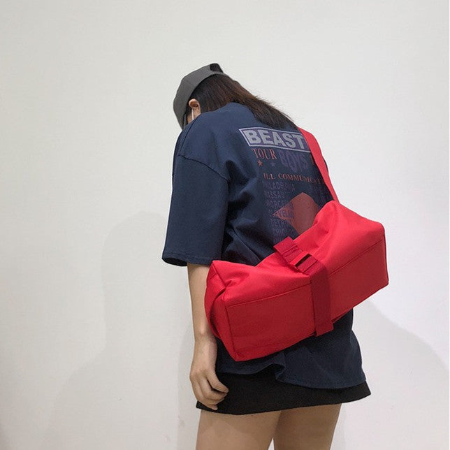 Person wearing a red bag over one shoulder with a plain background